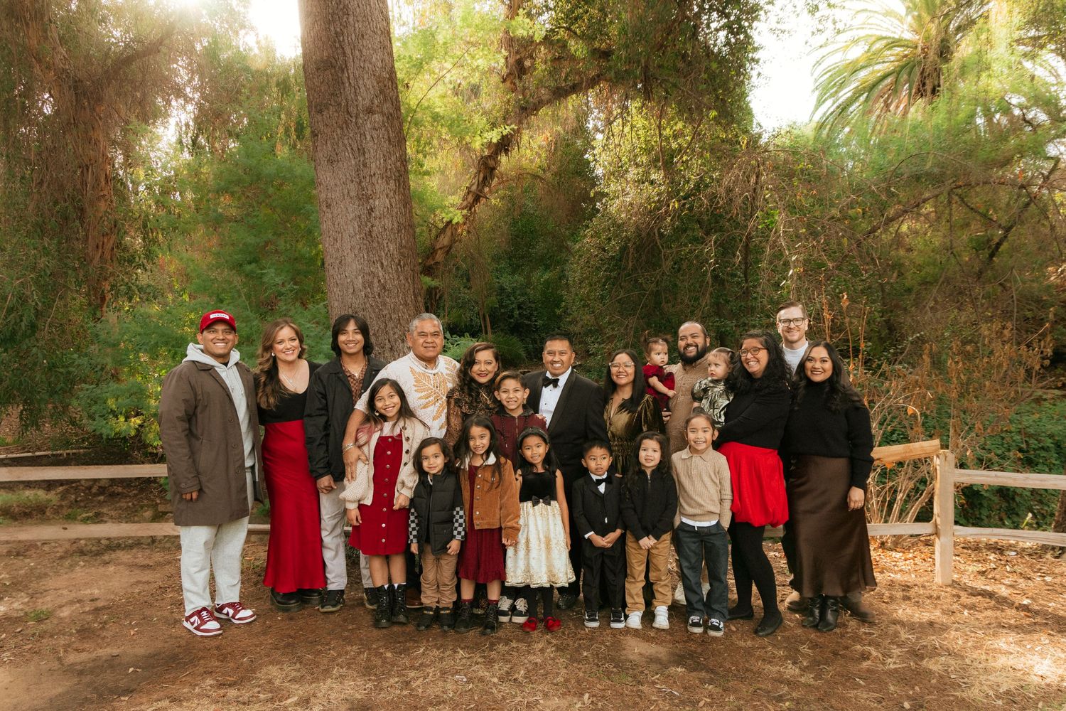 Large family group posed together outdoors in a wooded park setting on a sunny day.