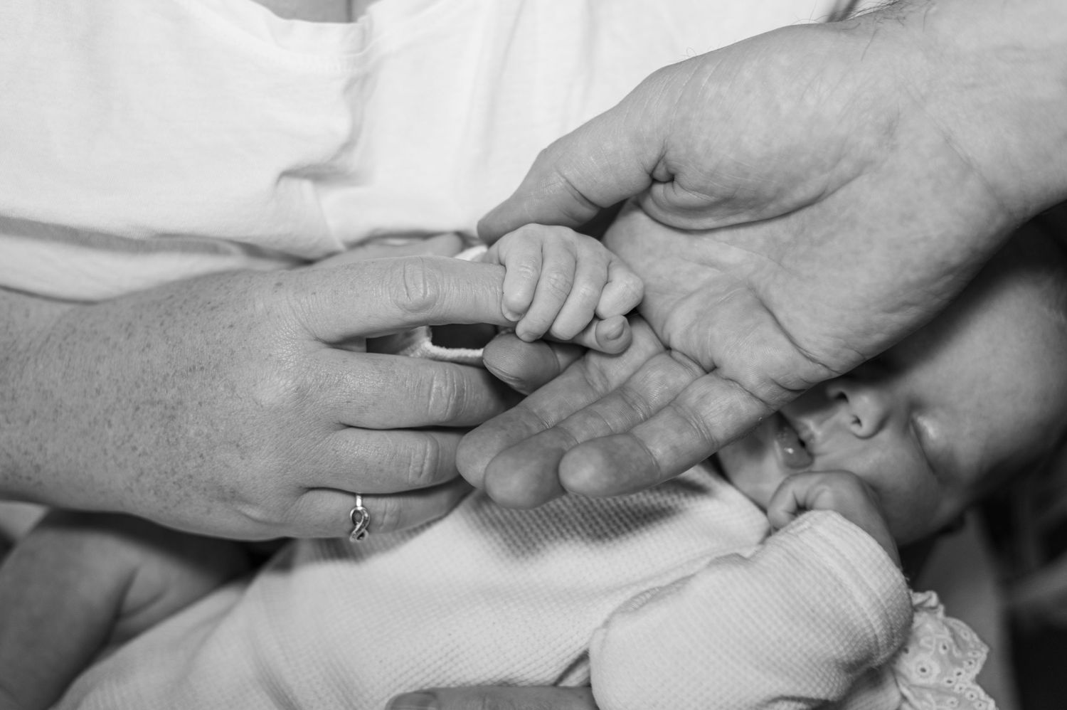 Intimate black and white moment with newborn wearing bow headband.