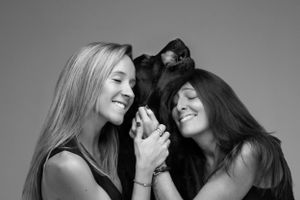 Three laughing friends holding hands and sharing a joyful moment in a black and white portrait.