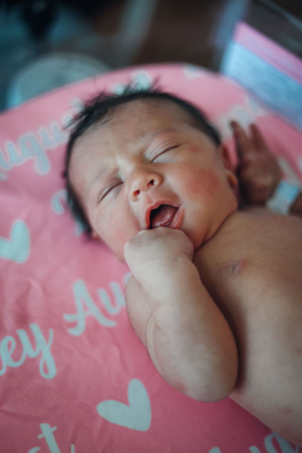 Sleeping baby in pink blanket with hands near face. Fresh 48 photography