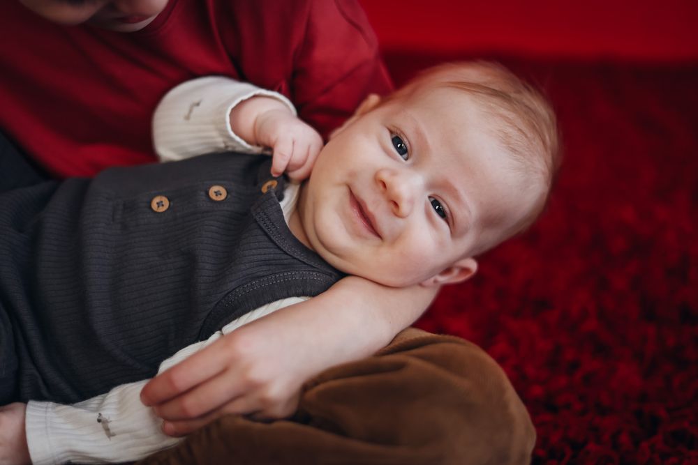 Close-up portrait against deep red background with dramatic lighting. Example of milestone photography