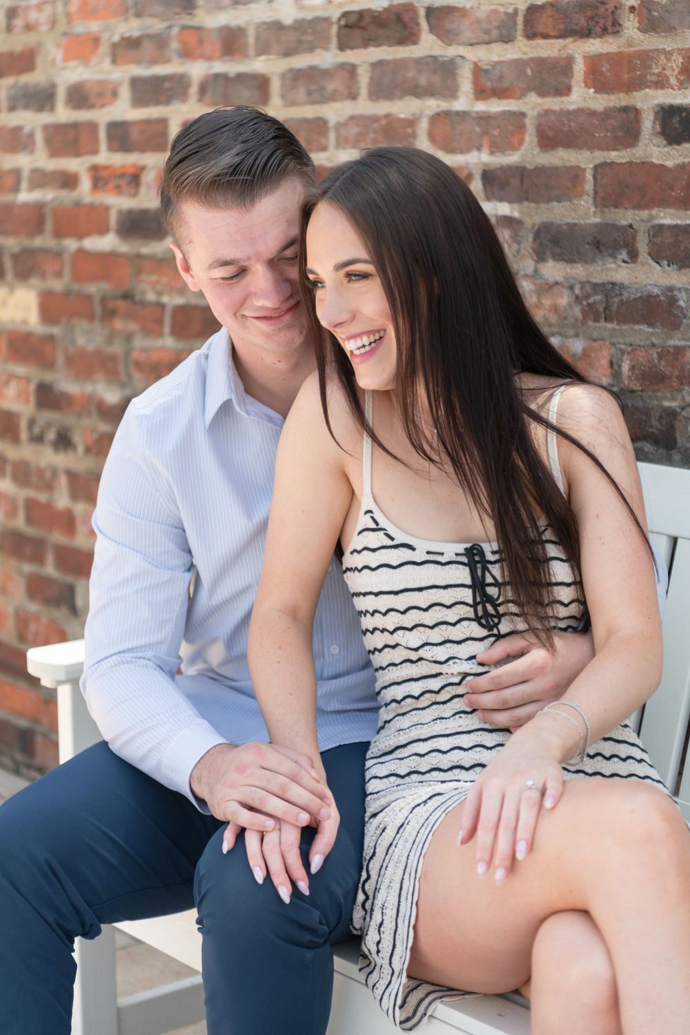 A couple sharing laughter while sitting together on an outdoor bench.