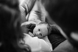 Black and white portrait of a baby resting on soft blankets.