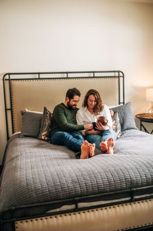 Couple sitting on gray bedding against an upholstered headboard.