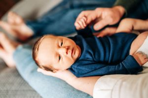 Baby in navy blue outfit resting on light blue bedding.