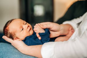 Close up of infant in navy blue outfit resting on blue bedding.