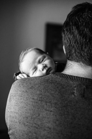 Black and white photo of peaceful baby resting on shoulder.