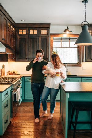 Modern kitchen interior with turquoise cabinets and dark wood details featuring a cozy family moment.