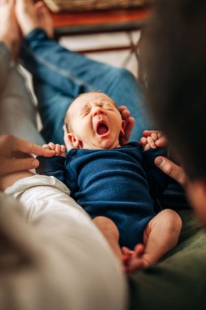 Close-up of a yawning newborn baby wearing a navy blue outfit.