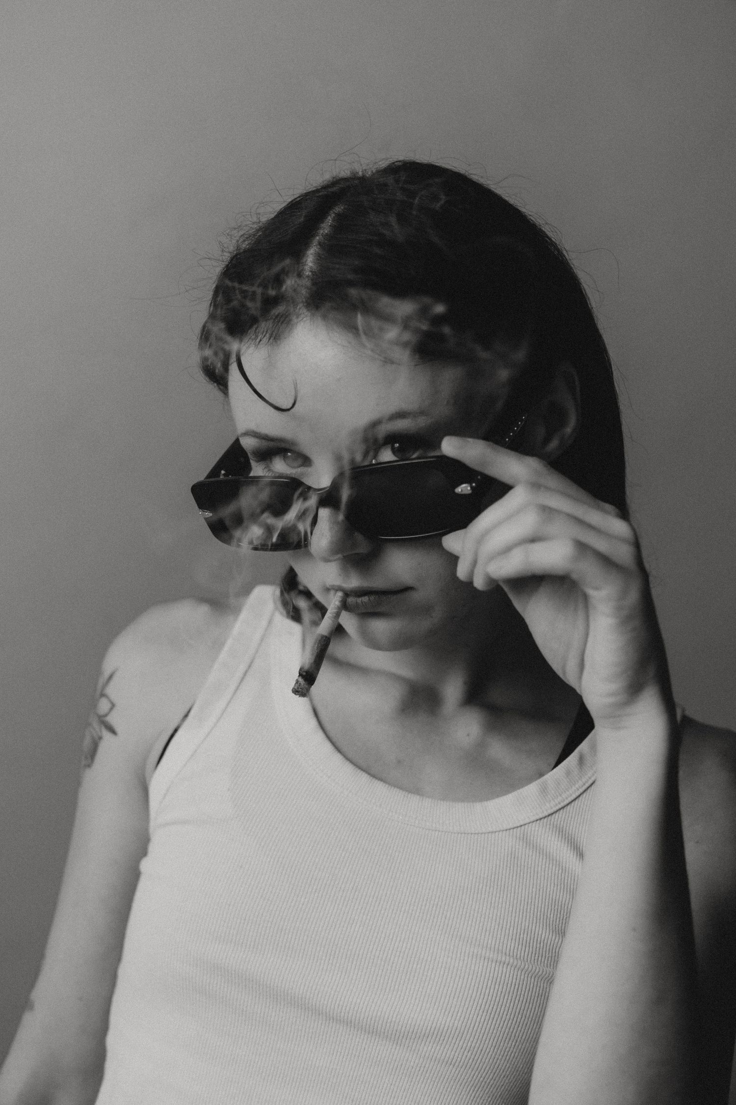 Black and white photo sequence of someone adjusting sunglasses while wearing a white tank top.