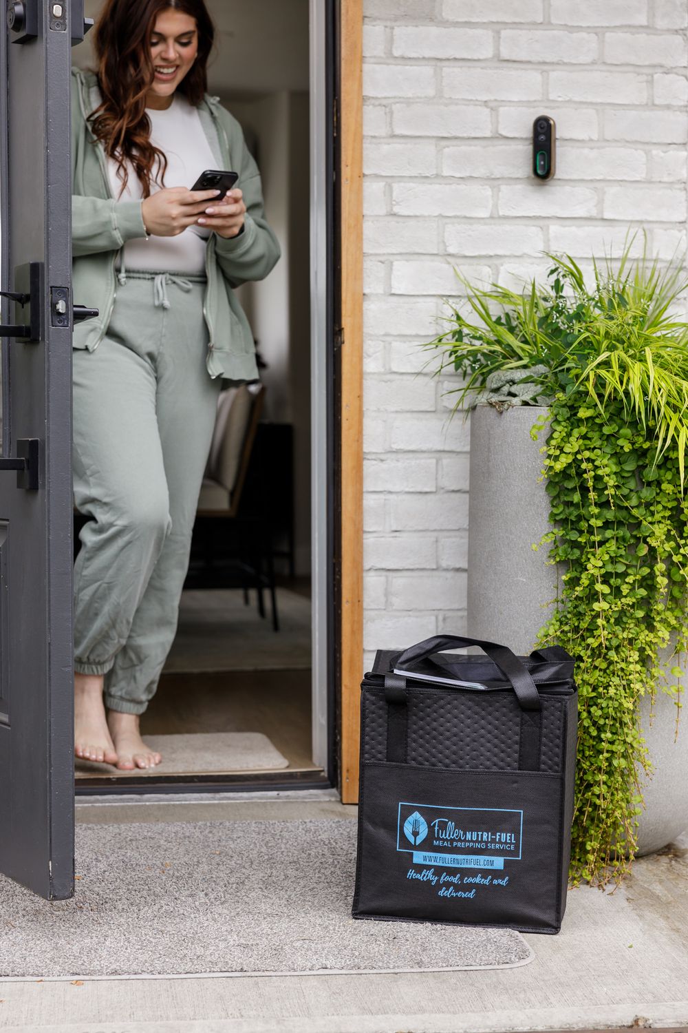 Fuller Nutri Fuel Seattle, WA Meal Prep delivery service for the busy professional product woman checking phone and door for noticifcation