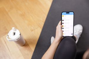 woman personal trainer mobile workout client app overhead shot of woman holding phone app open with water bottle sitting on yoga mat Seattle