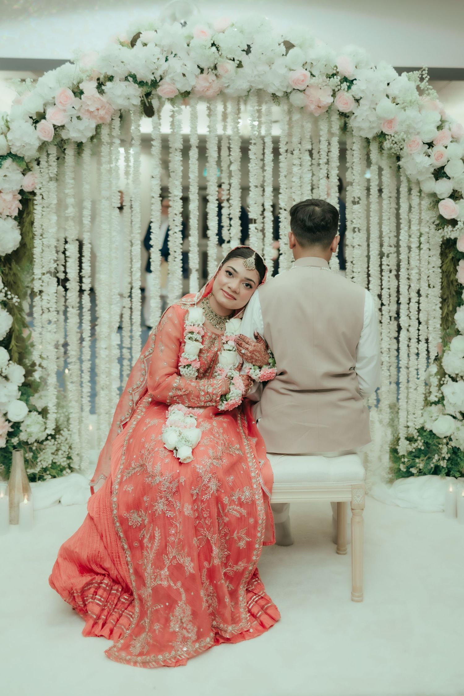 Wedding guests in traditional South Asian attire share a lighthearted moment at reception table.