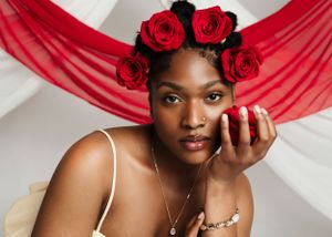 Portrait of a woman with red roses in her hair against draped red fabric.