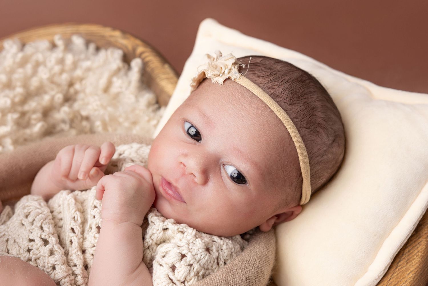 Baby wearing a delicate lace headband lies on soft cream fabric in a collage of sweet newborn portraits.