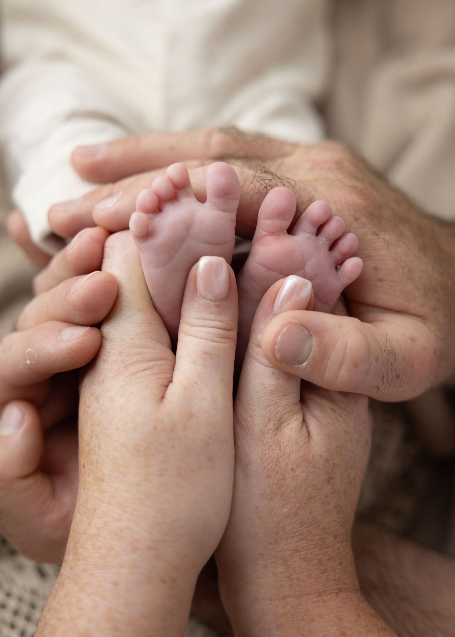 Two hands intertwined in a gentle embrace showing connection and intimacy against a soft beige background.