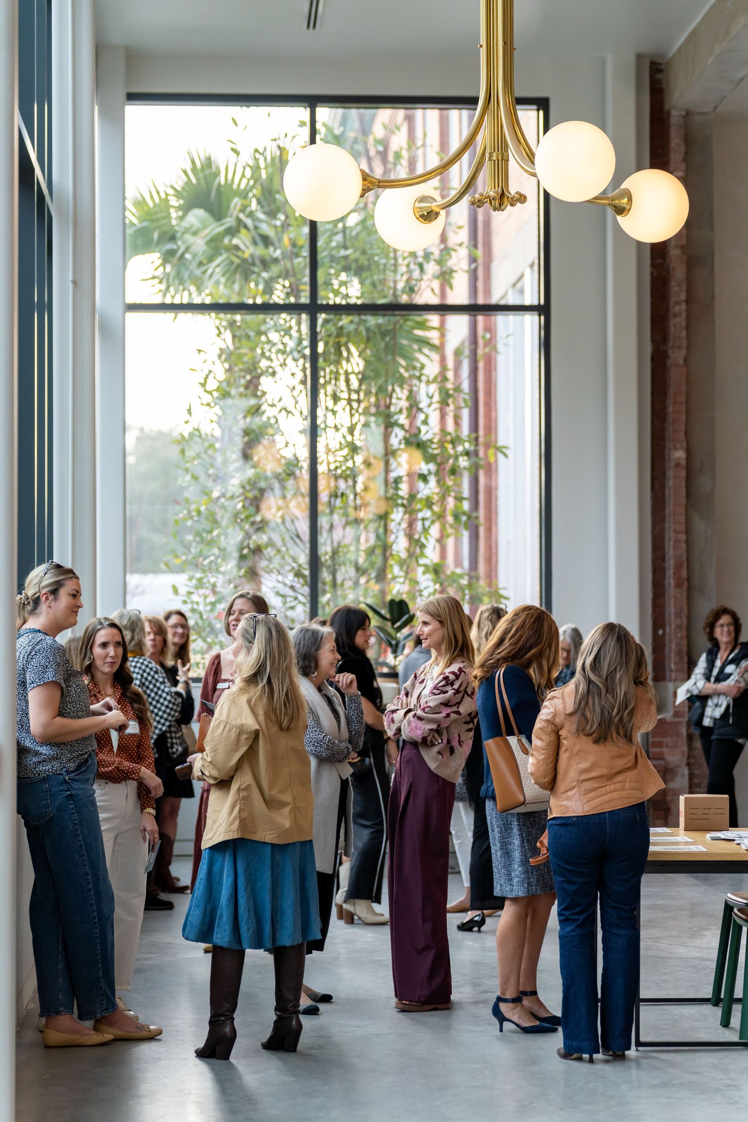 Group gathering in modern space with large windows and statement chandelier.