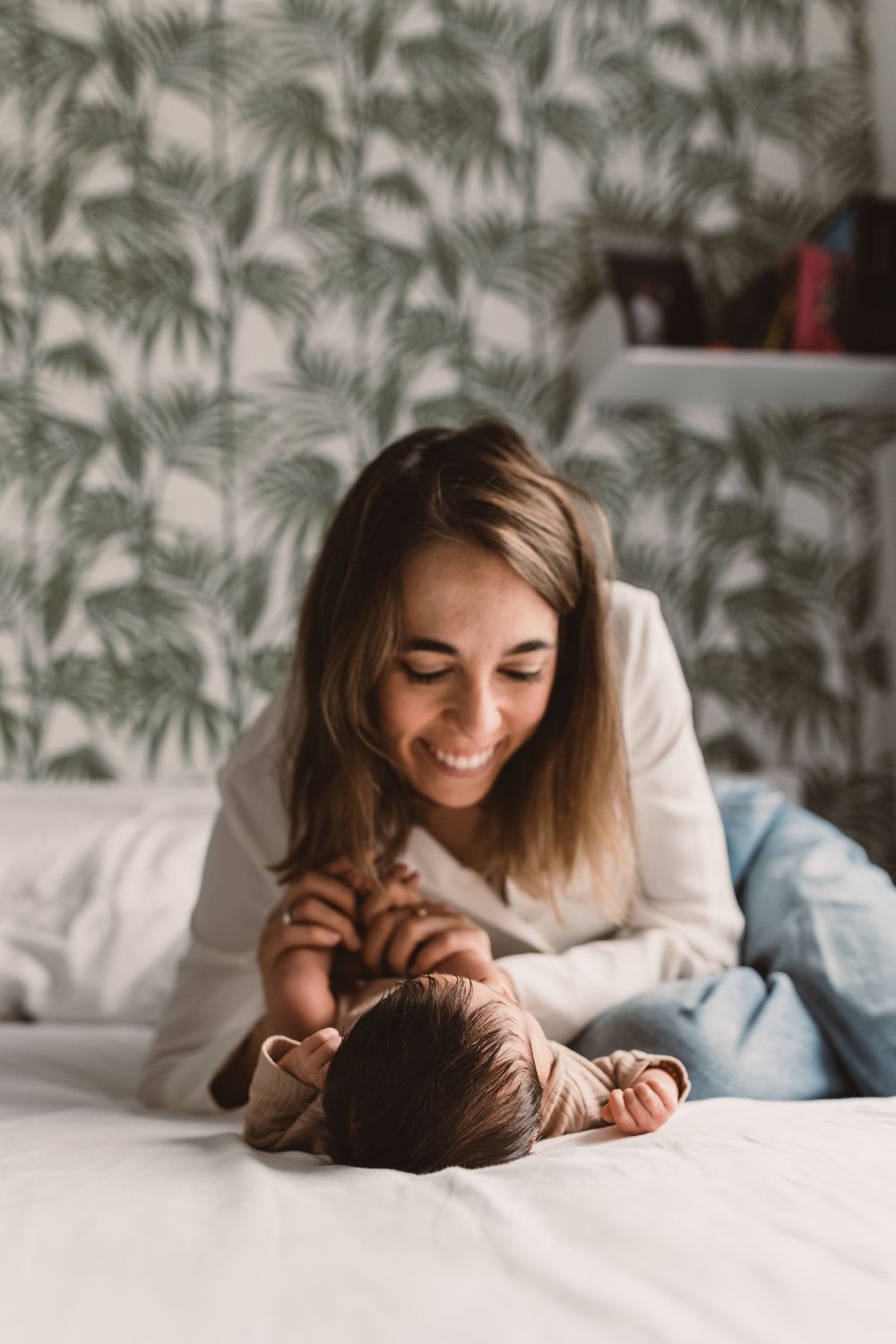 A mother having a tender moment with her newborn baby on a bed.