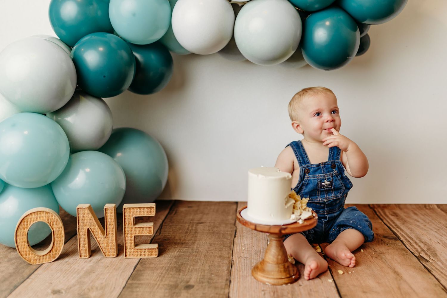 Baby milestone photo with teddy bears and peach balloon arch decoration.
