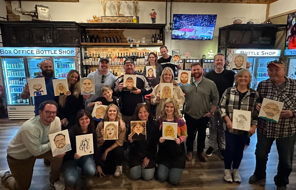 Group of art students displaying their completed paintings in a studio setting.