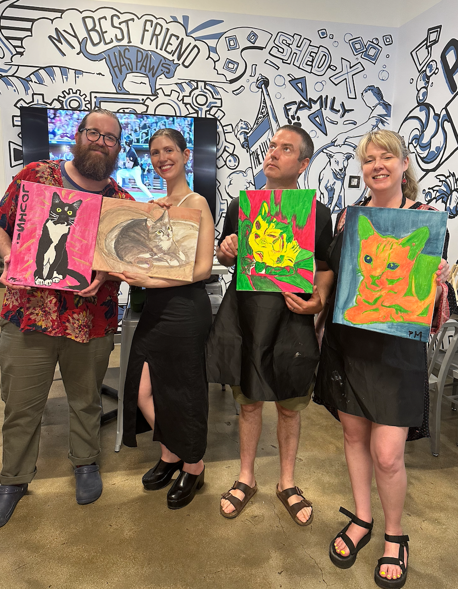 Group displaying colorful pet portrait paintings against a wall with doodle art background.
