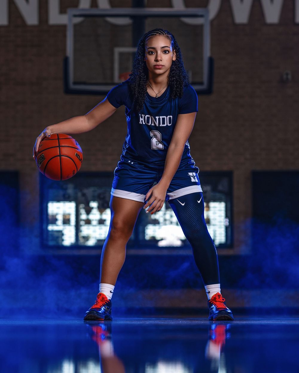 Basketball player in navy blue uniform dribbles while practicing on a shiny indoor court.