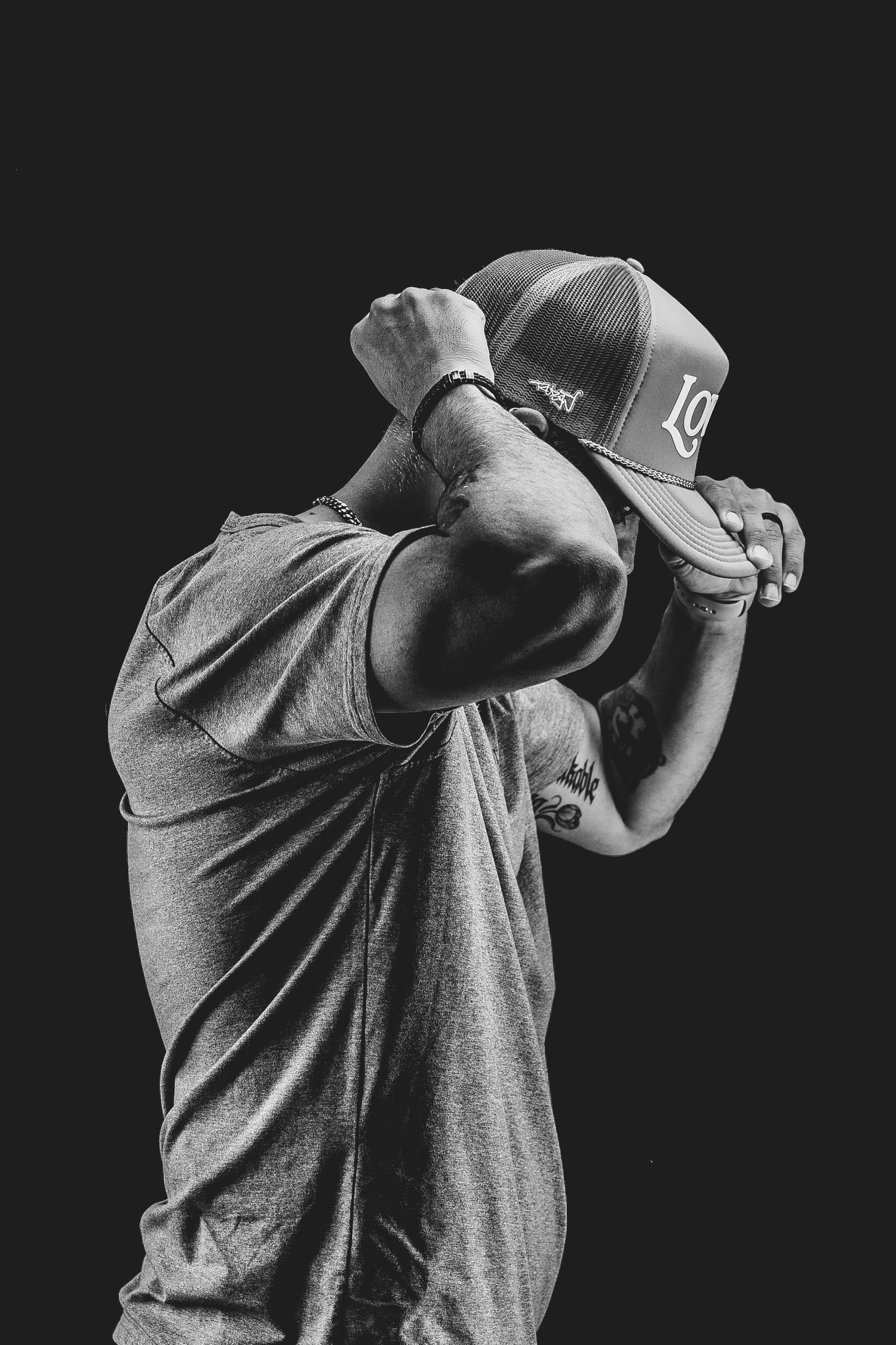 Cinematic black and white photo of person in athletic wear putting on a hat.