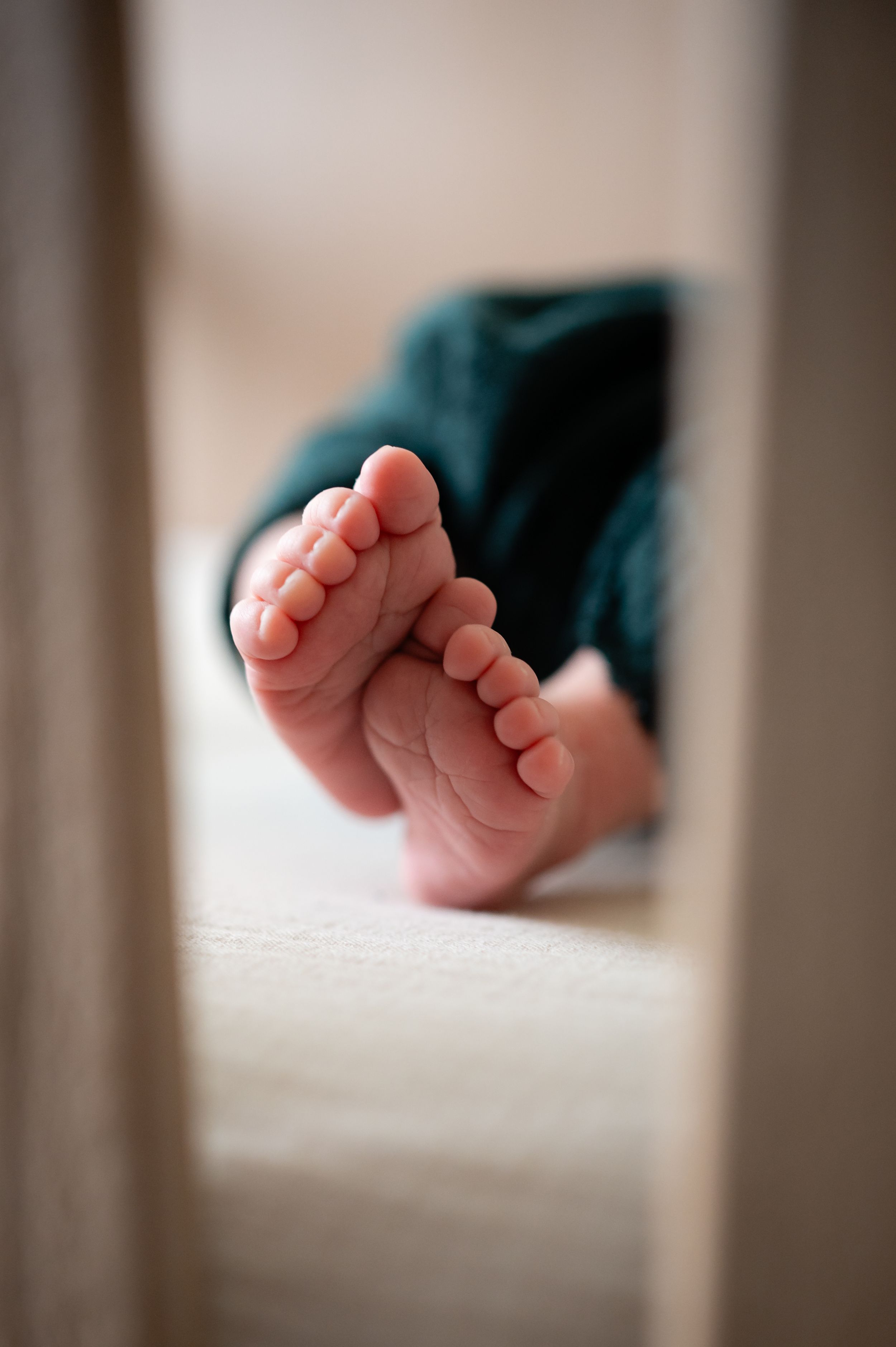 Tiny newborn foot detail against white bedding in soft focus.