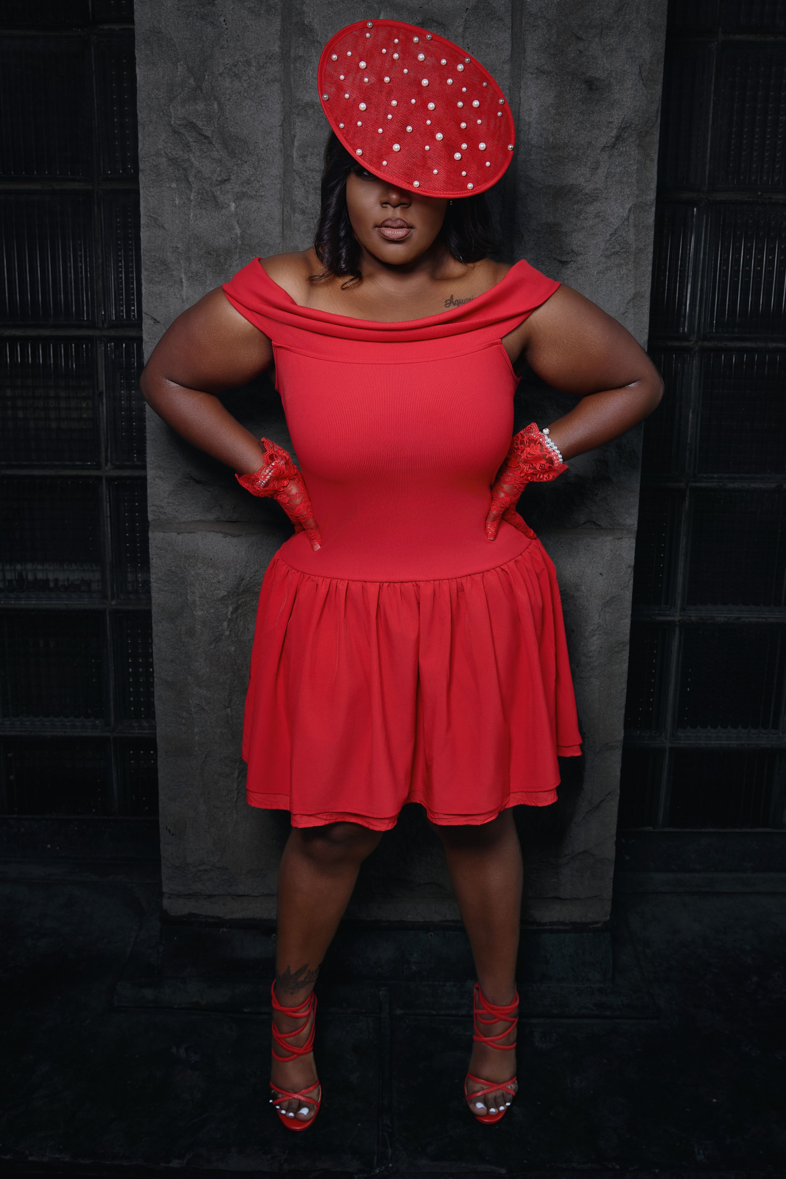 Fashion photo of red dress with polka dot details against dark background.