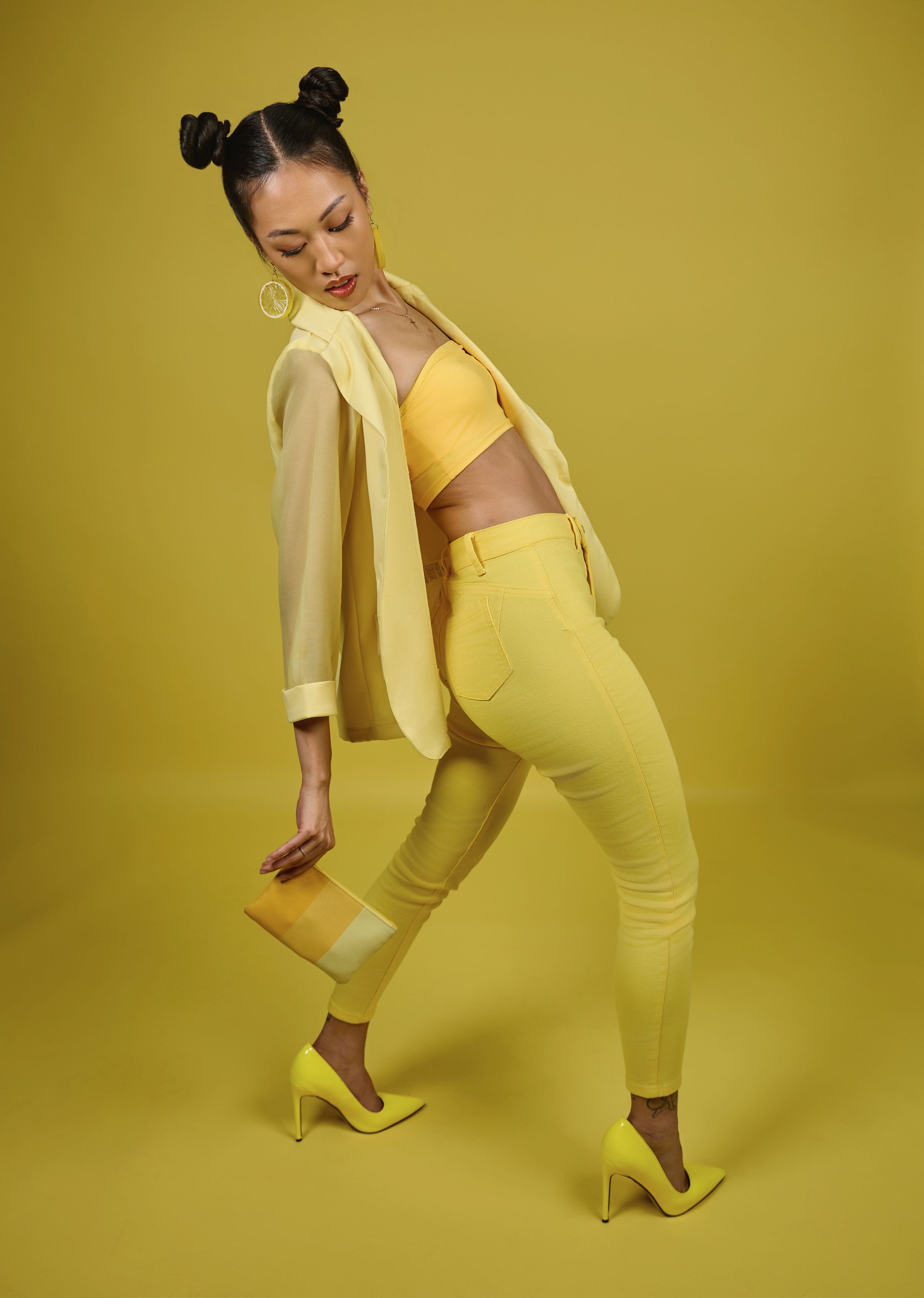 Dynamic fashion poses in all-yellow outfit against yellow backdrop.