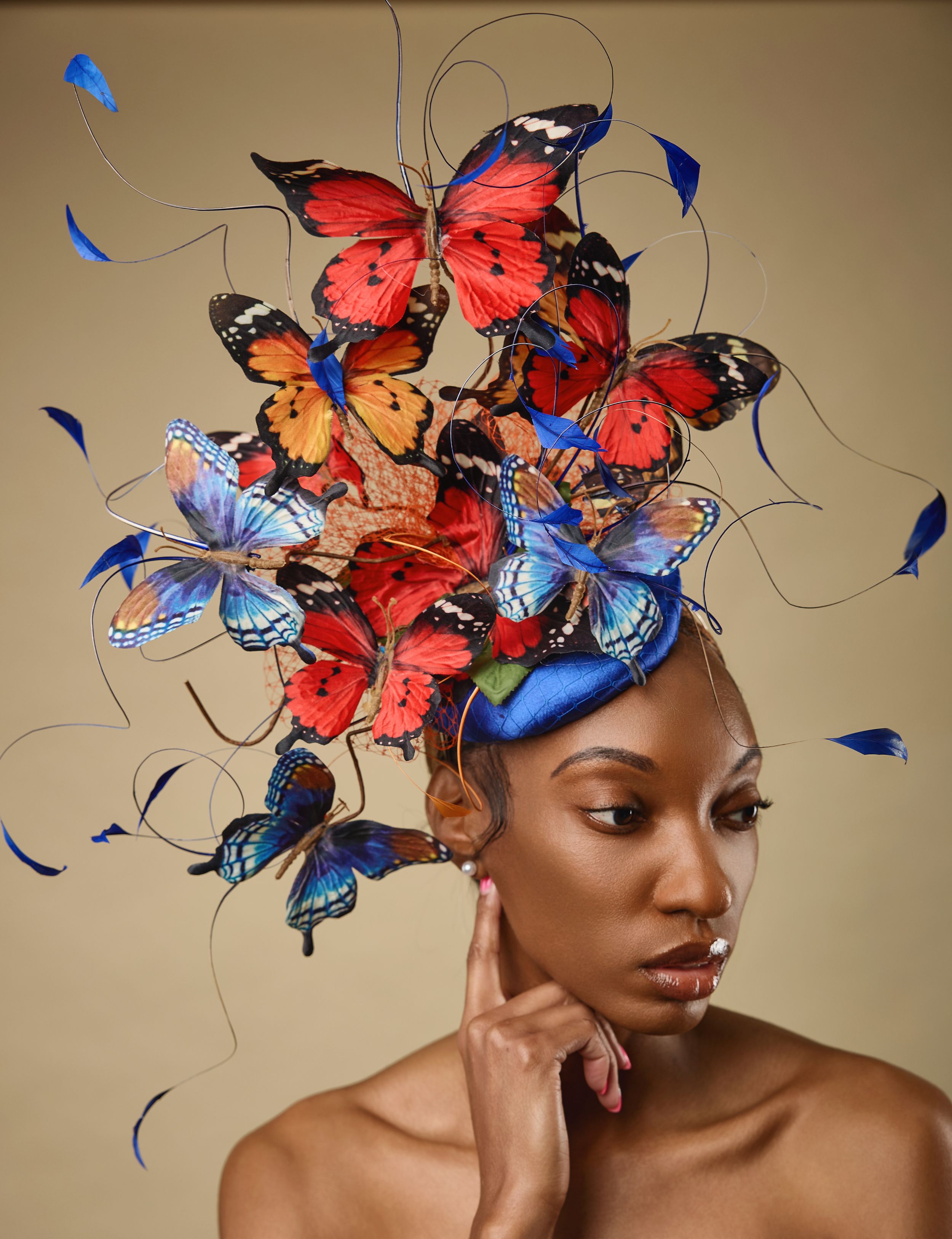 Creative beauty portrait with colorful butterfly headpiece against beige background.