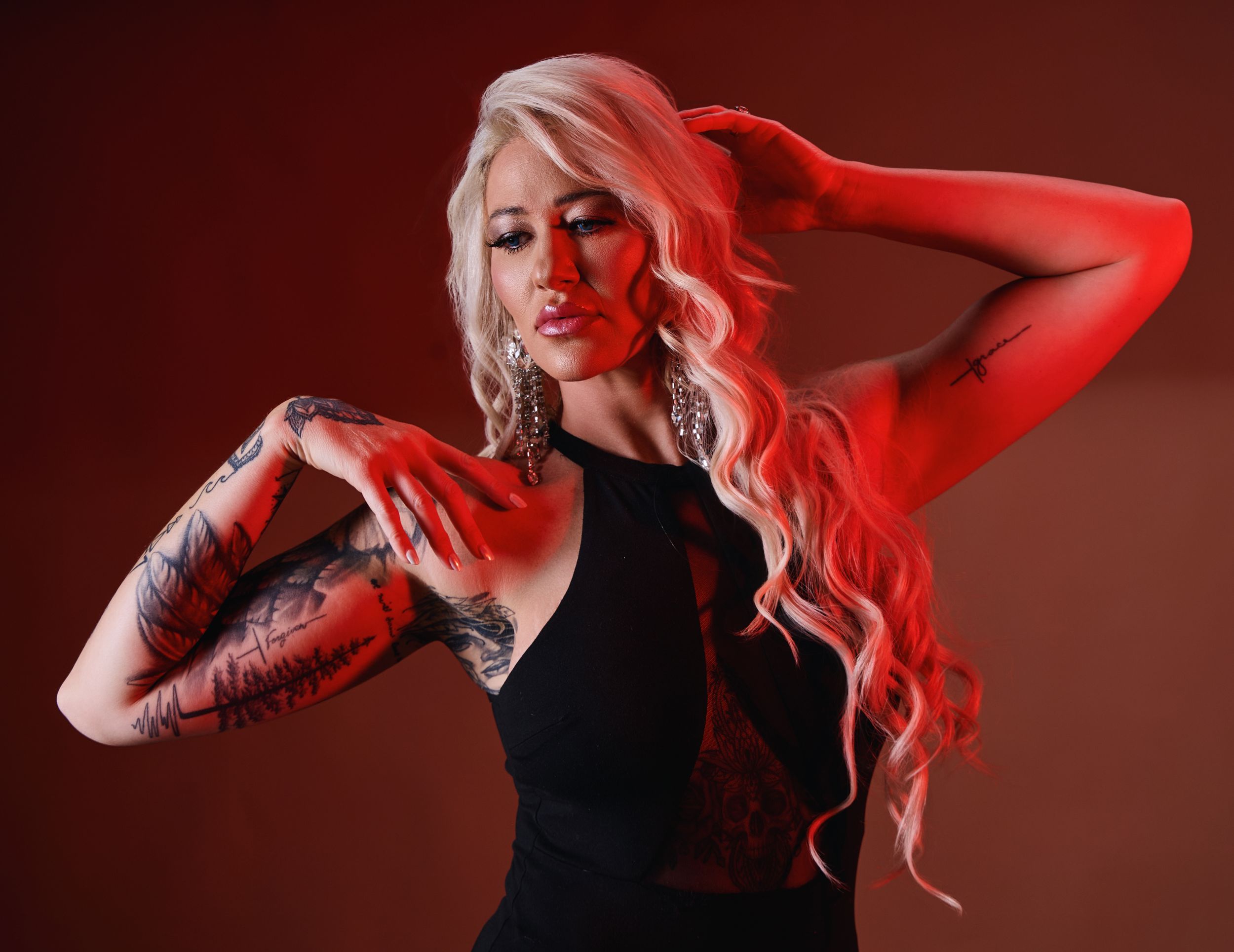 Model in black top poses with dramatic red lighting effect.