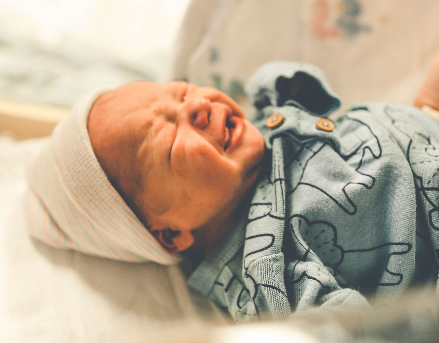 Newborn baby sleeping peacefully in cozy gray and white blankets.