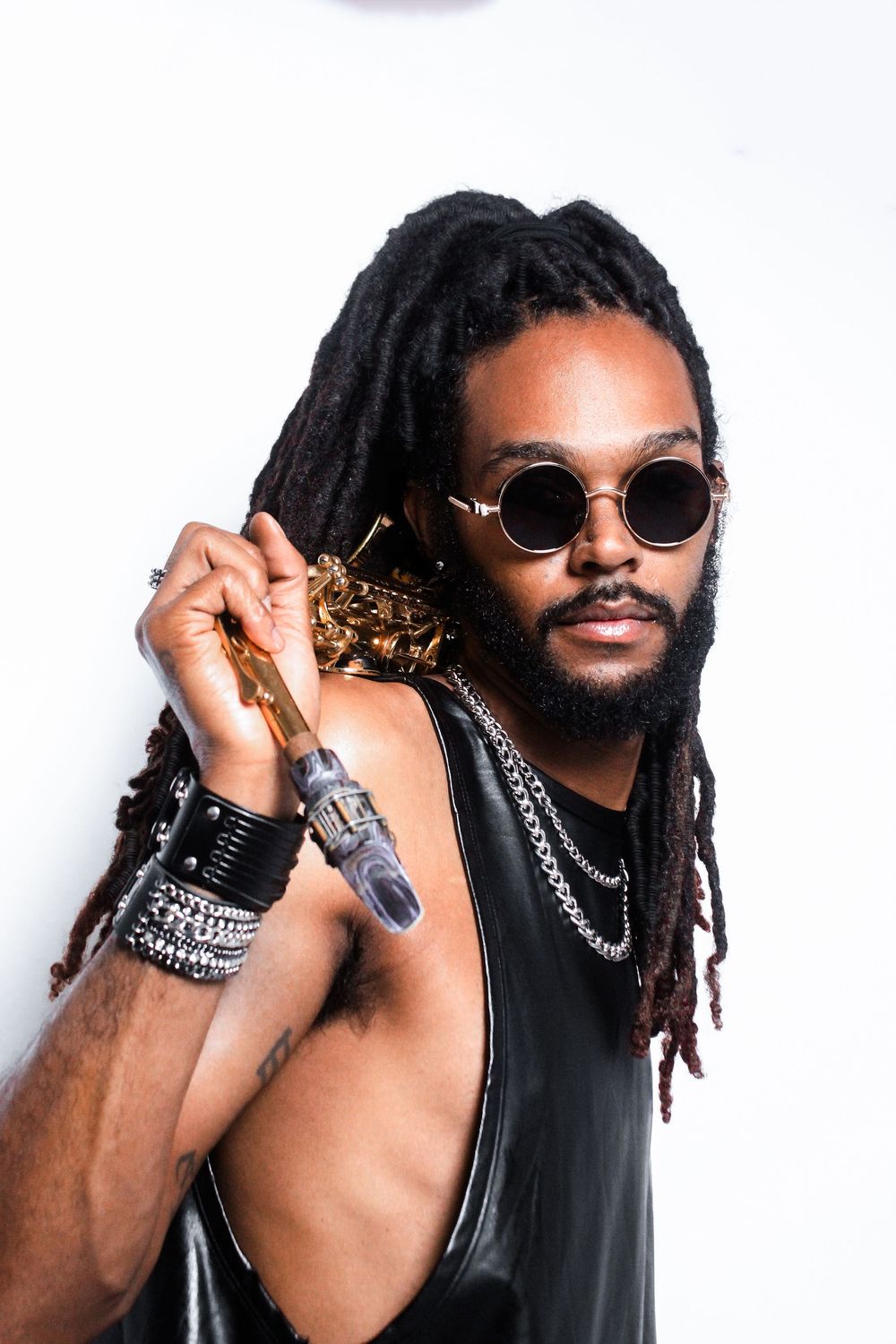 Musician with dreadlocks and sunglasses holding saxophone in artistic portrait.