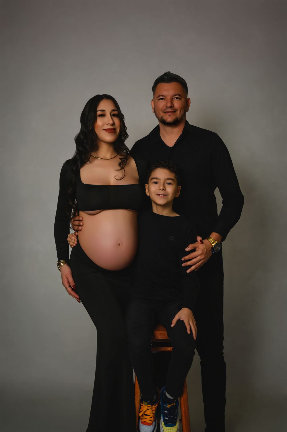 Family maternity photoshoot with couple and child wearing coordinated black outfits.