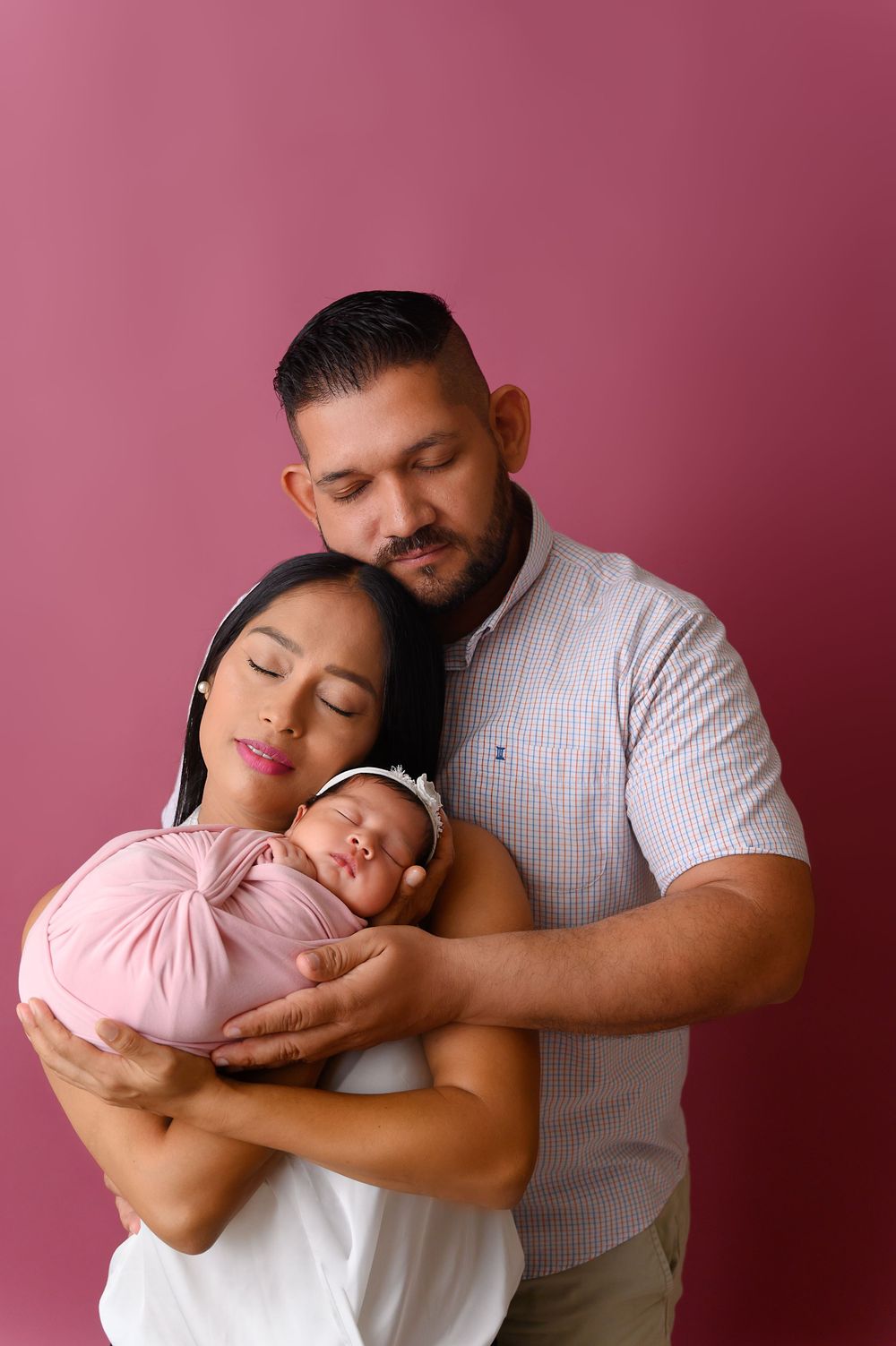 Tender family portraits against pink backdrop showing intimate embraces and peaceful moments.