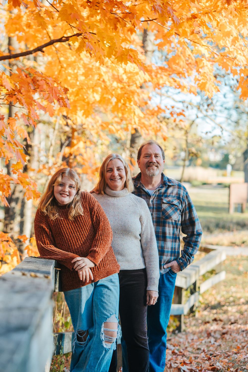 Autumn family photoshoot with vibrant orange foliage in the background.