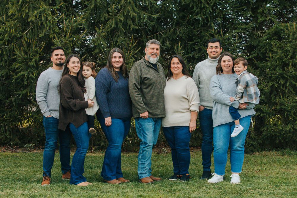 Group photo session in a lush green outdoor setting with matching denim outfits.