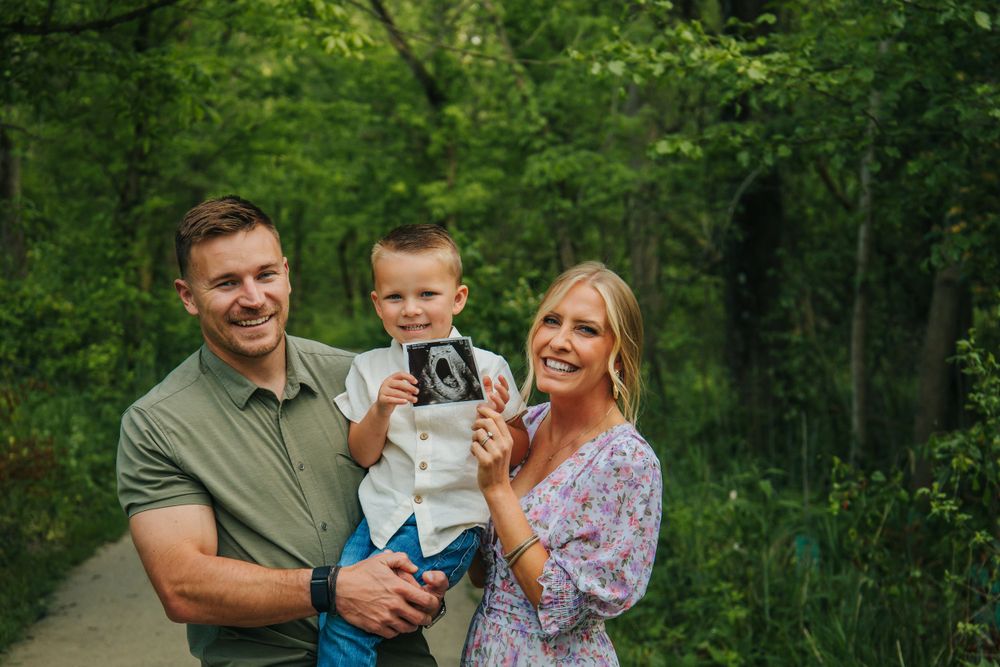Family enjoying a playful moment together in a lush green forest setting.