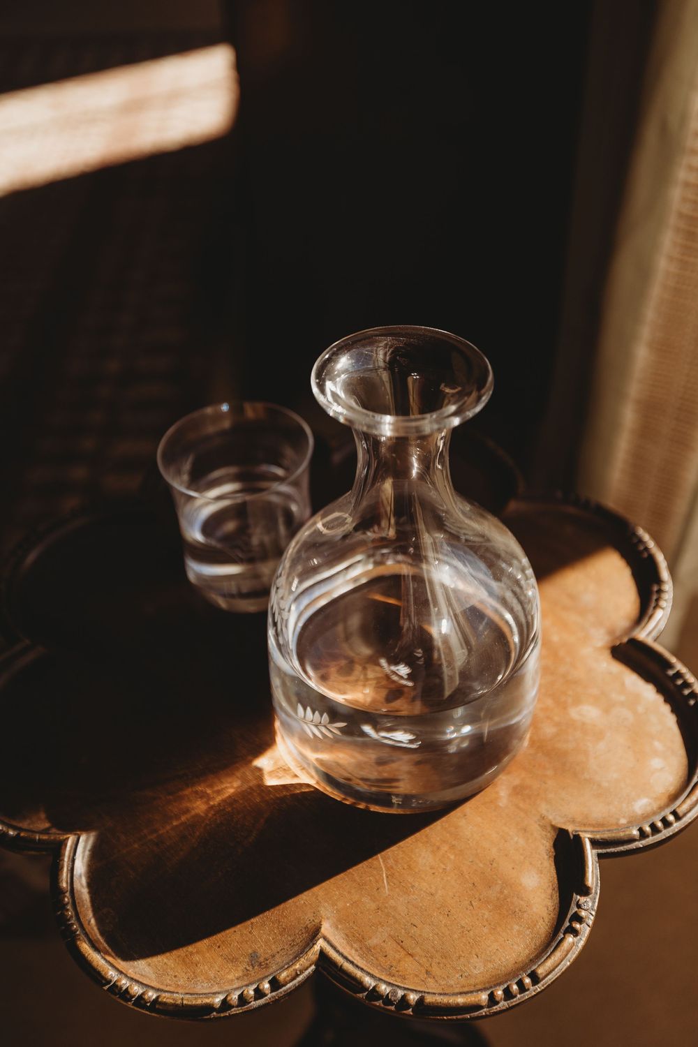 Wine glasses cast dramatic shadows on a wooden surface in warm lighting.