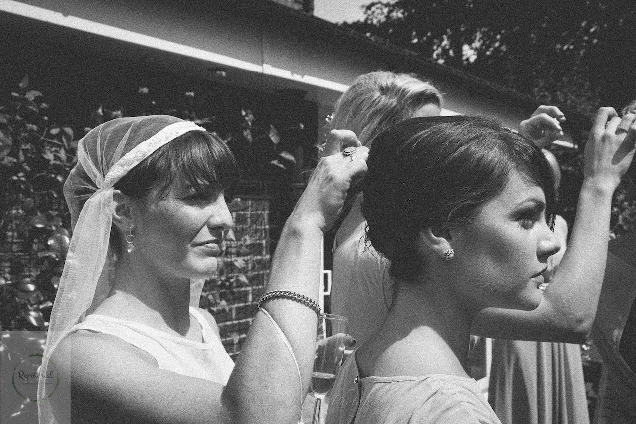 Wedding reportage photo of bride securing the hair of a bridesmaid
