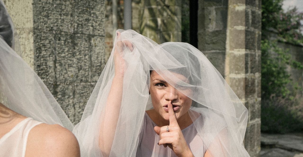 Reportage detail shot of bridesmaid hiding in the brides Weil during the wedding reception