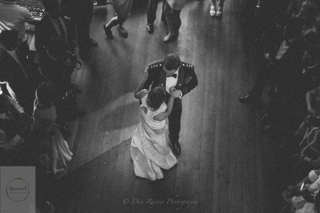 Wedding reportage photo of bride and groom enjoying first dance surrounded by guests