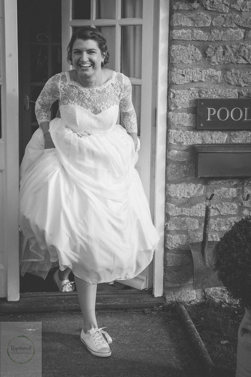 Wedding reportage photo of bride walking to the ceremony with trainers for her shoes