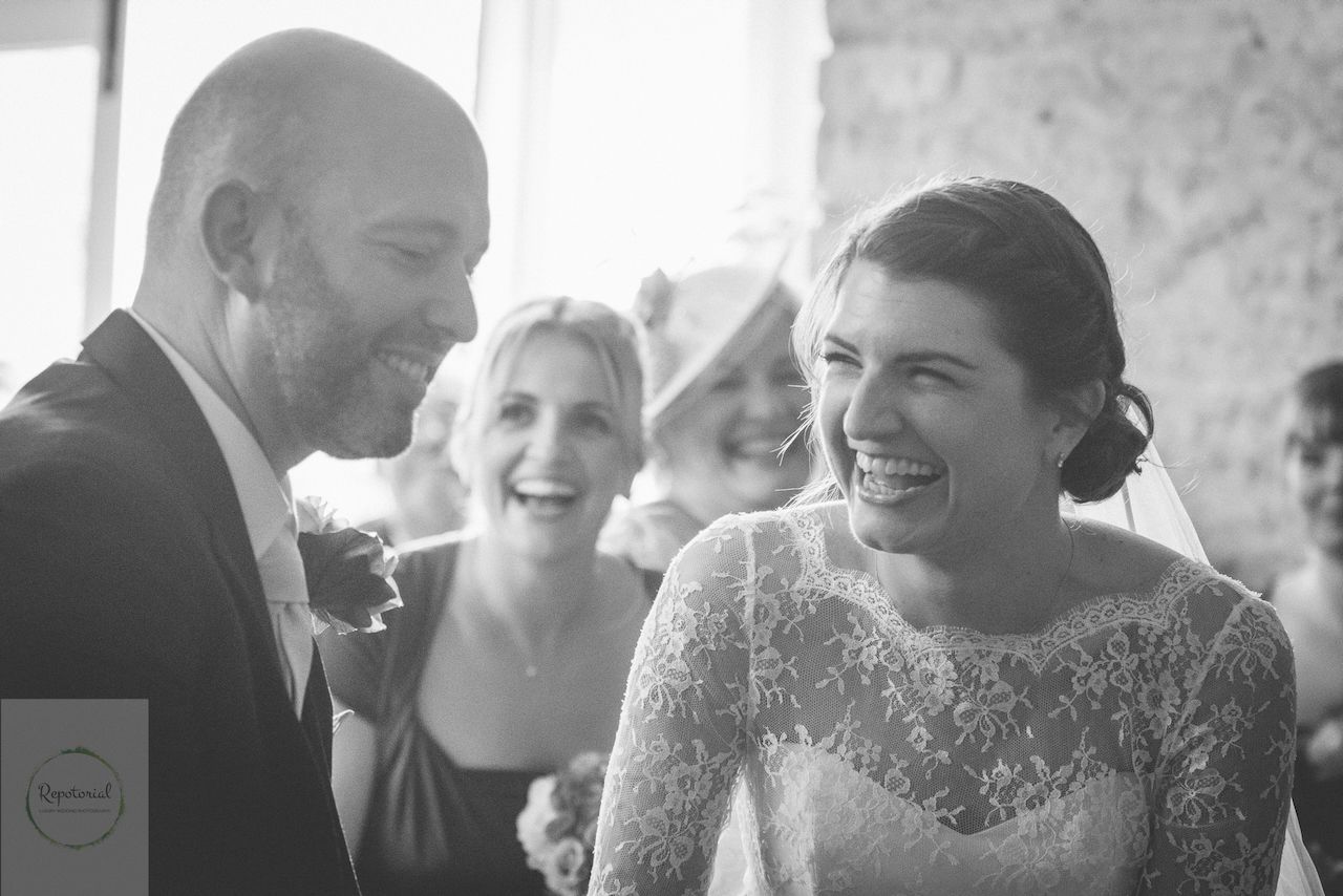 Bridge and groom laughing during ceremony captured in candid style. Stratton Court Barn