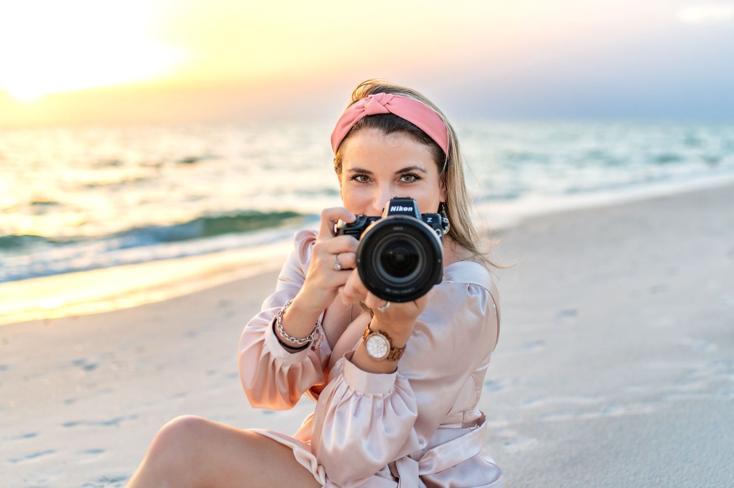 Photographer with camera shooting at beach during golden hour.