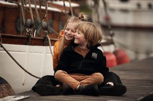 Candid family moment with laughter and hugs in a natural outdoor setting Siblings sharing a playful moment together