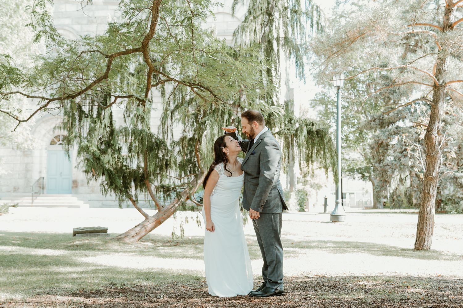 A couple shares a romantic moment under Spanish moss draped trees in a dreamy outdoor setting.