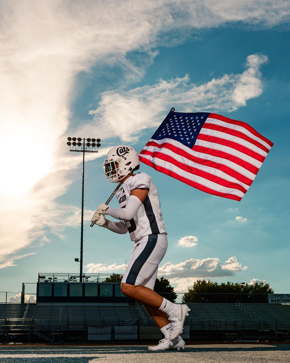 Cienega senior football player running with American flag on football field in Tucson, AZ