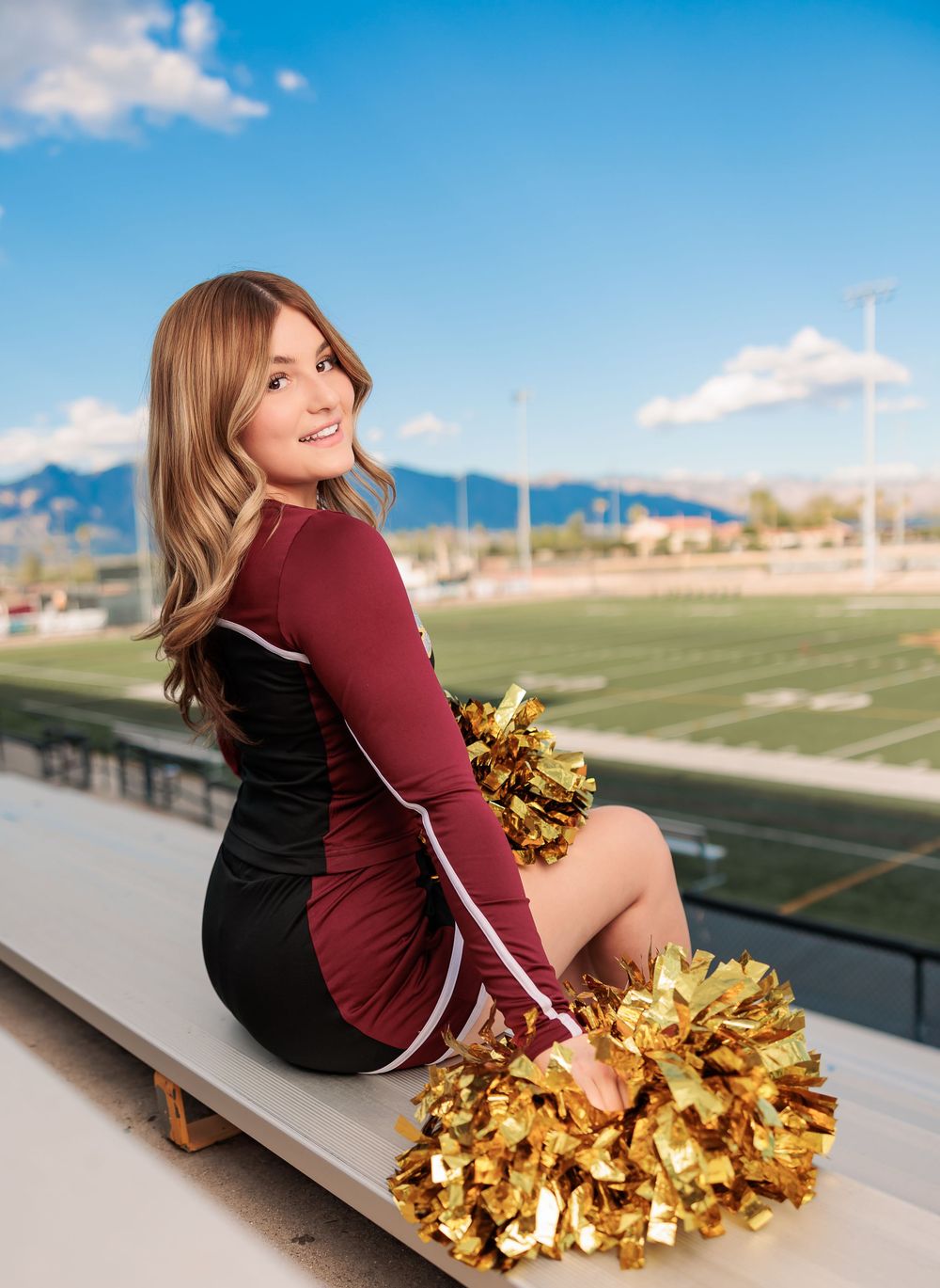 Salpointe High School Senior Cheerleader posing in uniform with poms on bleachers Tucson, AZ